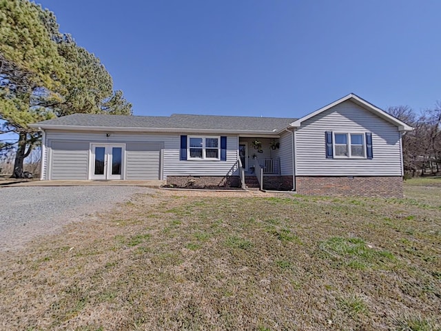 single story home featuring gravel driveway, an attached garage, french doors, and a front yard