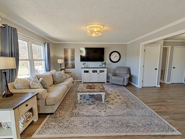 living area with baseboards, a textured ceiling, ornamental molding, and wood finished floors