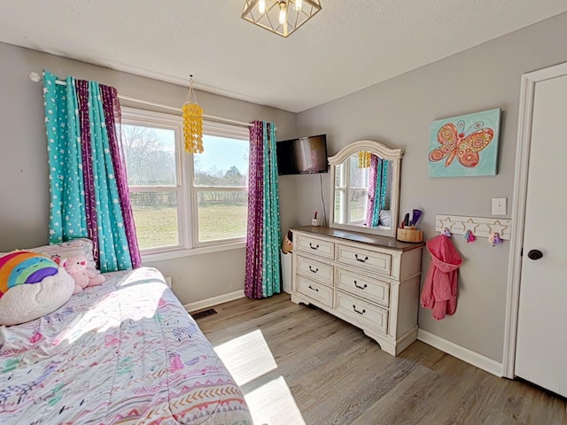 bedroom featuring visible vents, baseboards, light wood-style flooring, and a textured ceiling