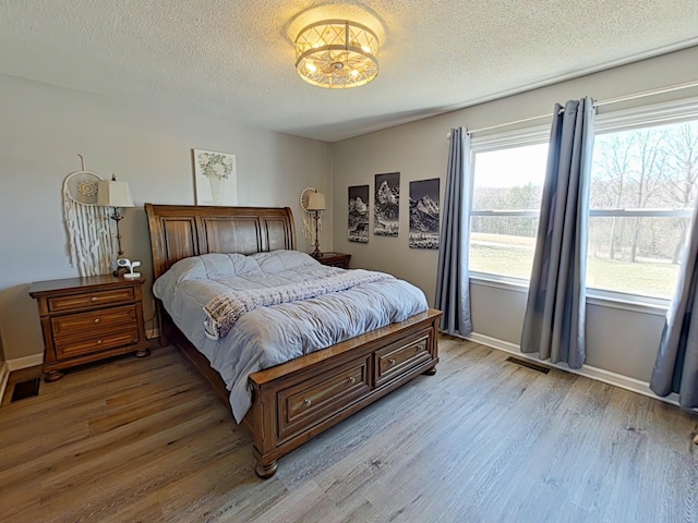 bedroom with light wood-style flooring, visible vents, and a textured ceiling