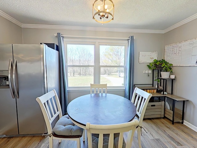 dining space with light wood-type flooring, a notable chandelier, crown molding, and a textured ceiling