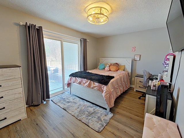 bedroom with a textured ceiling, light wood finished floors, and access to exterior