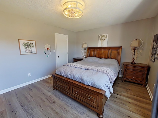 bedroom with a textured ceiling, light wood-type flooring, and baseboards