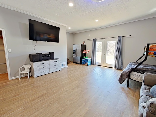 interior space featuring a textured ceiling, french doors, crown molding, and light wood-style floors