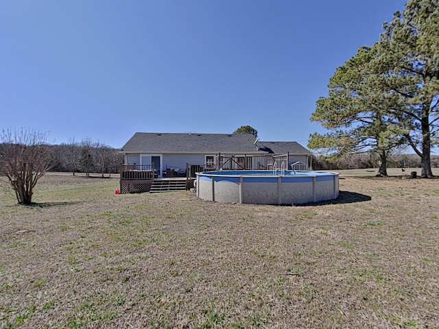 rear view of property featuring an outdoor pool, a lawn, and a wooden deck