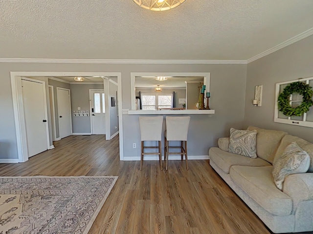 living room featuring crown molding, a textured ceiling, baseboards, and wood finished floors