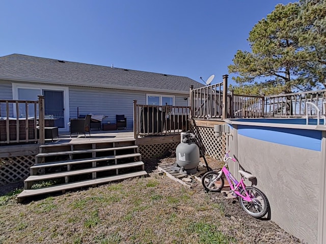 back of property with a shingled roof and a wooden deck