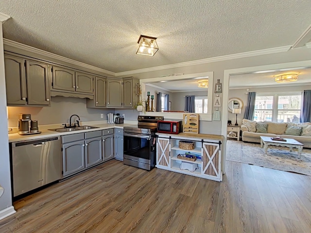 kitchen with a sink, light countertops, appliances with stainless steel finishes, ornamental molding, and dark wood-style floors