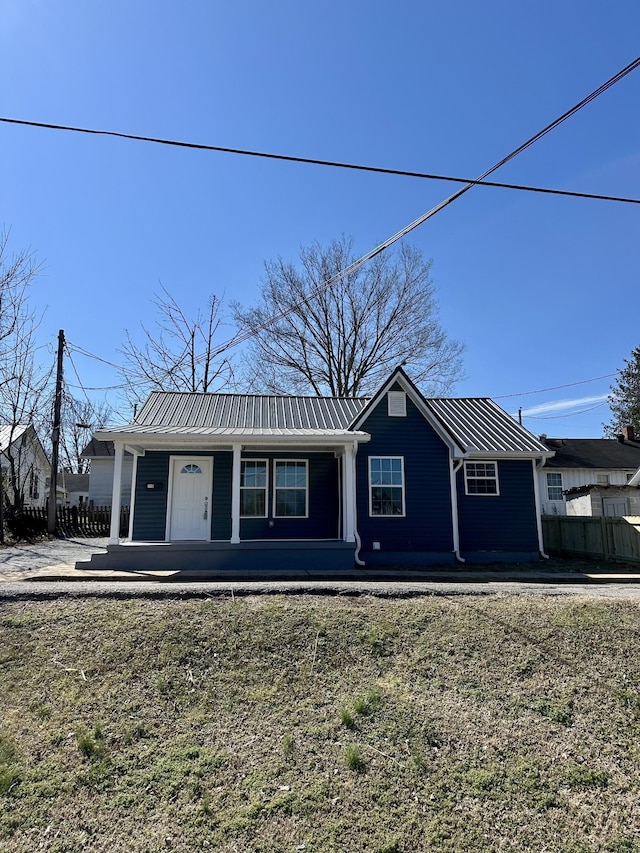 view of front of home with a porch, fence, and metal roof