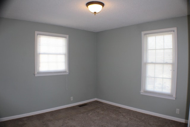 unfurnished room featuring baseboards, visible vents, and dark colored carpet