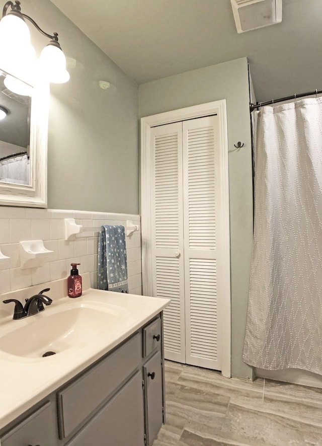 bathroom with a wainscoted wall, tile walls, curtained shower, vanity, and wood finished floors