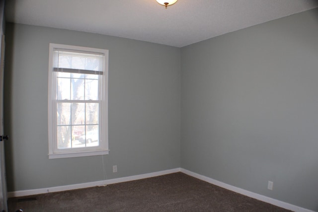 unfurnished room with dark colored carpet and baseboards