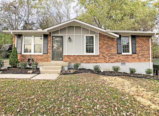 view of front of home featuring board and batten siding, a front yard, crawl space, and brick siding