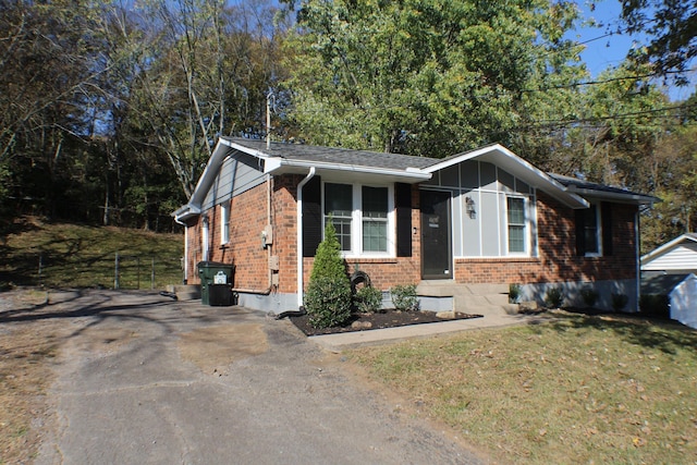 view of front of house with driveway, a front yard, and brick siding