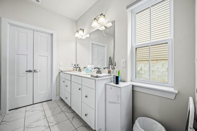 full bath featuring marble finish floor, plenty of natural light, a sink, and double vanity