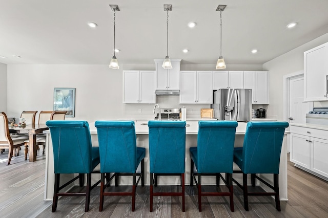 kitchen featuring dark wood-style flooring, a center island with sink, light countertops, appliances with stainless steel finishes, and white cabinets