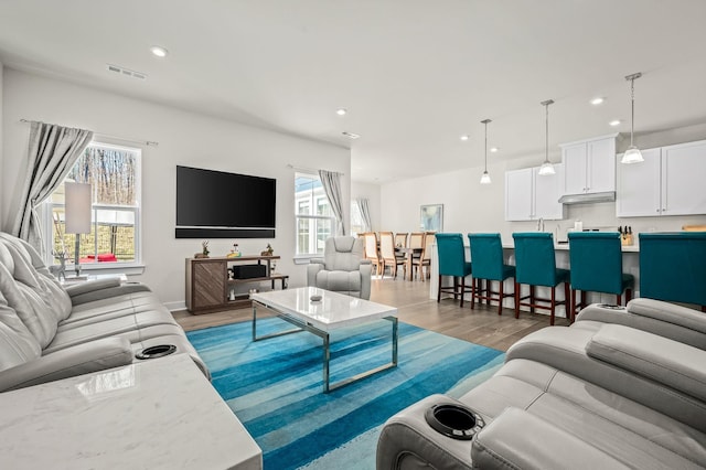 living room with baseboards, wood finished floors, visible vents, and recessed lighting