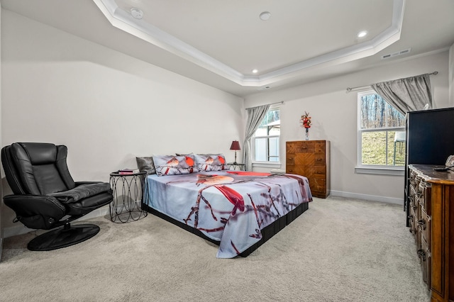 bedroom featuring a tray ceiling, light colored carpet, visible vents, and multiple windows