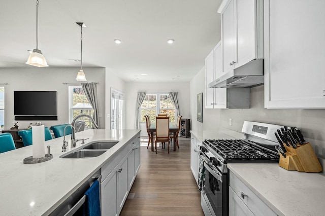 kitchen featuring stainless steel range with gas cooktop, white cabinetry, a sink, wood finished floors, and under cabinet range hood