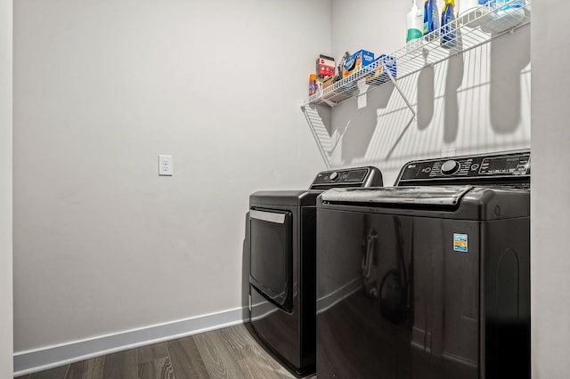 laundry area featuring baseboards, laundry area, dark wood finished floors, and washer and dryer