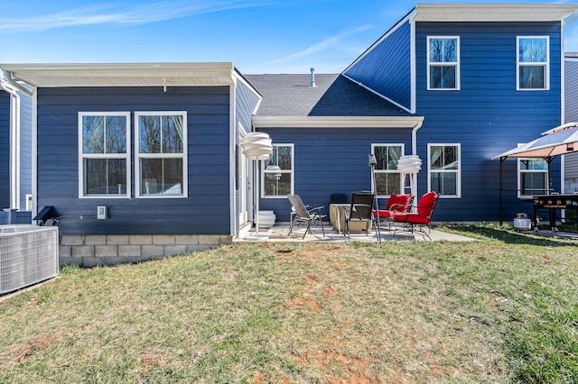 rear view of house featuring cooling unit, roof with shingles, a patio, and a lawn