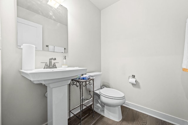 bathroom with toilet, baseboards, and wood finished floors