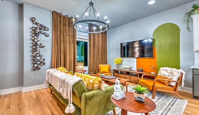 sitting room featuring light wood finished floors, baseboards, arched walkways, and a notable chandelier