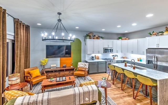 kitchen with white cabinets, light wood-style flooring, appliances with stainless steel finishes, light countertops, and a sink