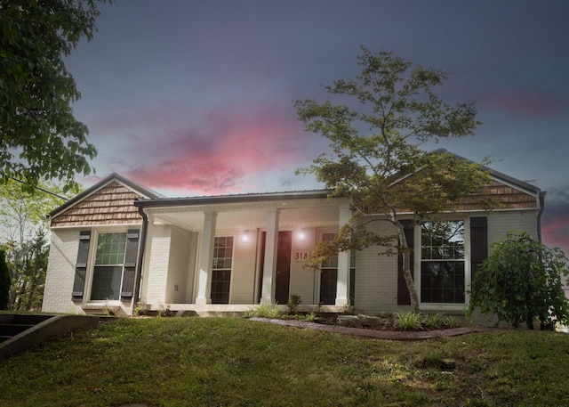 view of front of house featuring a yard and brick siding