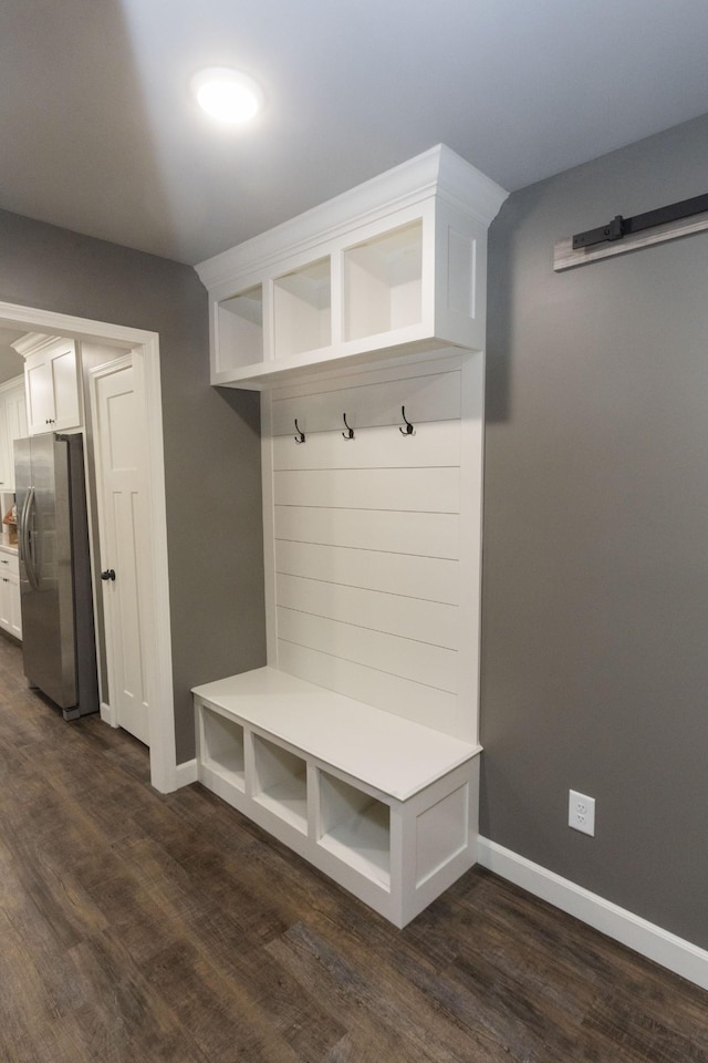 mudroom featuring dark wood-type flooring and baseboards