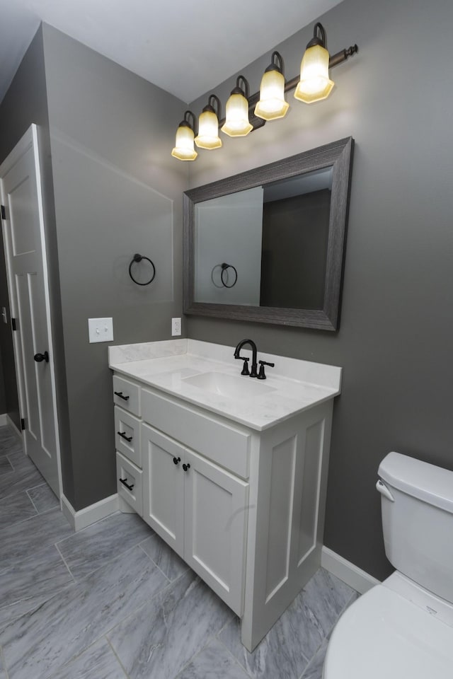 bathroom with marble finish floor, baseboards, vanity, and toilet