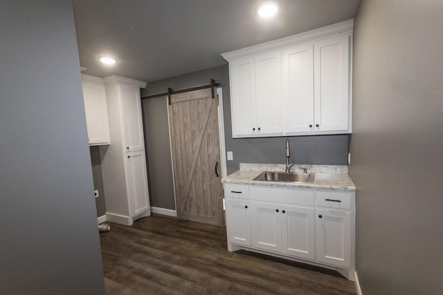 kitchen featuring dark wood-style flooring, white cabinets, a sink, and a barn door