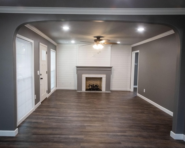 unfurnished living room with arched walkways, dark wood-style flooring, a fireplace, crown molding, and baseboards