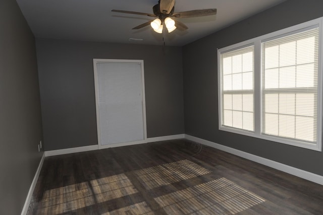 unfurnished room with ceiling fan, dark wood finished floors, and baseboards