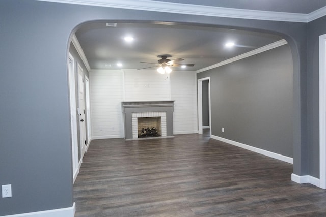 unfurnished living room featuring baseboards, dark wood-type flooring, a brick fireplace, and crown molding