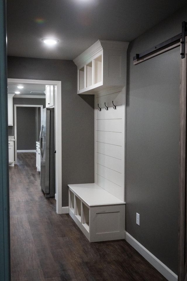 mudroom featuring dark wood finished floors, baseboards, and a barn door