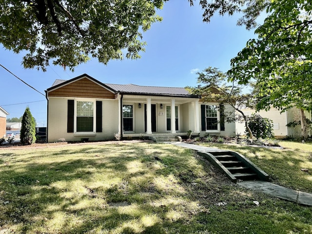 ranch-style home featuring covered porch, a front yard, metal roof, and brick siding