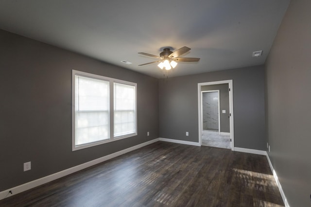 empty room featuring dark wood-style floors, baseboards, and visible vents