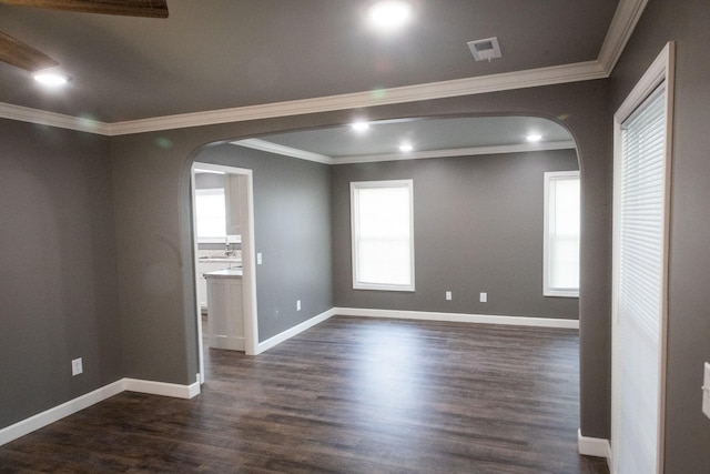 spare room with baseboards, arched walkways, dark wood finished floors, ornamental molding, and recessed lighting