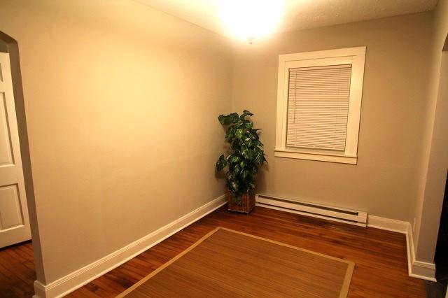 empty room with a baseboard radiator, baseboards, and wood finished floors