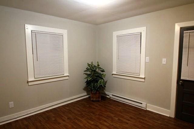 empty room with a baseboard radiator, baseboards, and wood finished floors