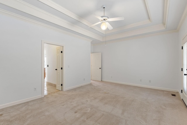 unfurnished bedroom with light carpet, baseboards, visible vents, a tray ceiling, and crown molding