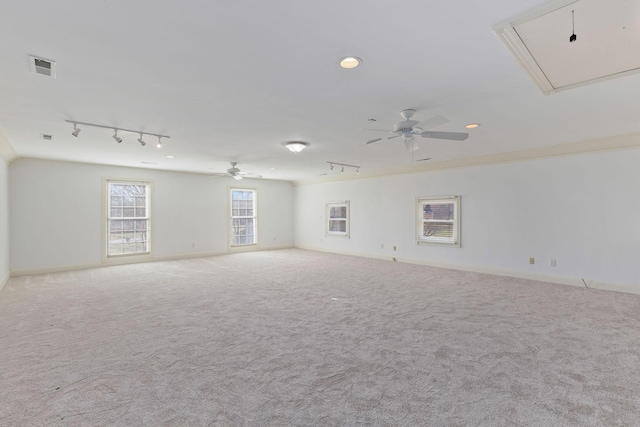 carpeted empty room featuring visible vents, a ceiling fan, baseboards, attic access, and track lighting