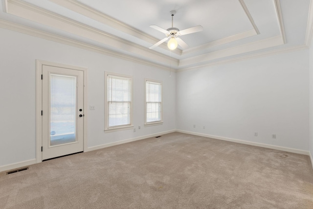 empty room with light carpet, baseboards, a raised ceiling, and crown molding