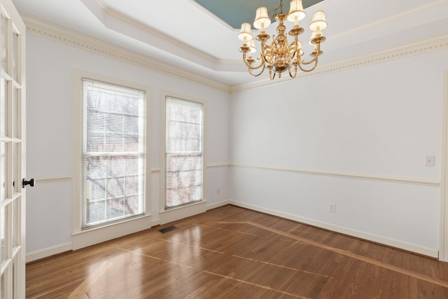 unfurnished room with a notable chandelier, visible vents, a raised ceiling, and wood finished floors