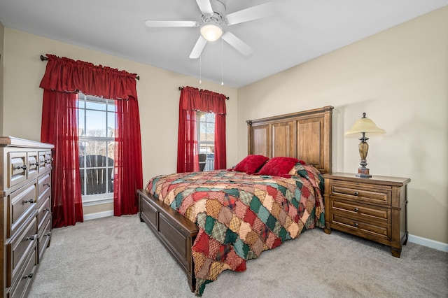 bedroom with ceiling fan, baseboards, and light colored carpet