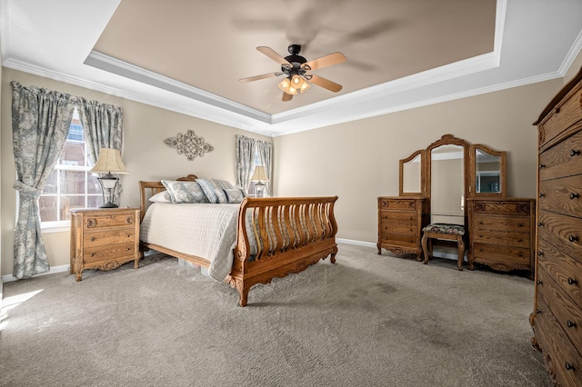 carpeted bedroom featuring ornamental molding, ceiling fan, a tray ceiling, and baseboards