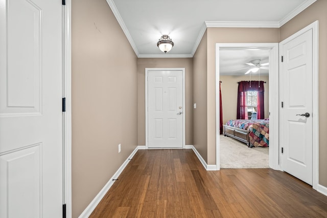 doorway to outside with crown molding, dark wood finished floors, a ceiling fan, and baseboards