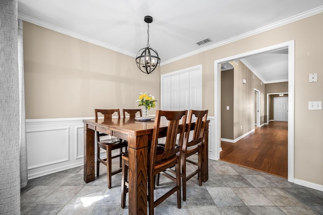 dining area with a chandelier, a decorative wall, a wainscoted wall, visible vents, and crown molding