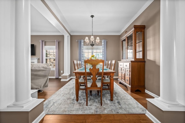 dining area with ornate columns, dark wood finished floors, and an inviting chandelier